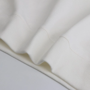 Close-up of premium heavy cotton ribbed hem on a minimalist white crewneck sweatshirt