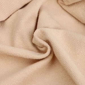 Macro shot of thick French Terry fabric texture and ribbed edge detail on apricot hoodie