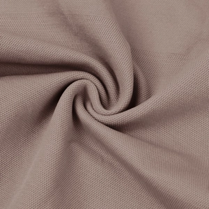 Detailaufnahme von braunem Strickstoff mit Wabenstruktur und weichem Faltenwurf