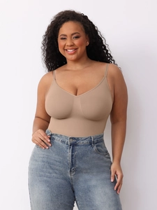 Front view of seamless beige shapewear bodysuit paired with blue jeans on a curvy model