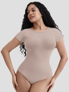 Close-up of beige short sleeve bodysuit with reinforced tummy control panel on high-stretch fabric
