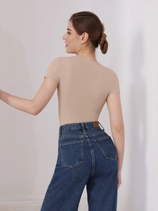 Rear view of a beige short sleeve bodysuit paired with high-waisted blue jeans