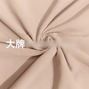 Dettaglio del tessuto beige a doppio strato che mostra la texture liscia del body