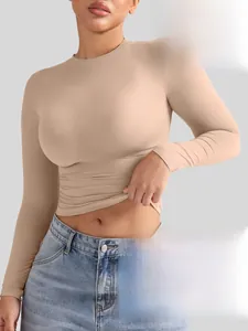 Gros plan d'un haut moulant beige à manches longues en tissu élastique mat et soyeux