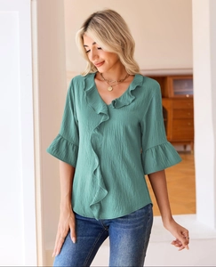 Close-up of ruffled V-neckline and bell sleeves on a teal pleated casual blouse