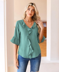 Detail of sage green ruffled top with V-neckline and textured fabric on a fashion model
