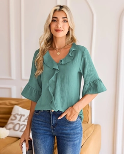 Close-up of turquoise V-neck blouse with ruffled collar and pleated lantern sleeves