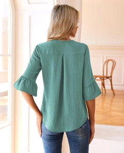 Detail of teal long-sleeve blouse with textured vertical pleats and ruffled cuffs