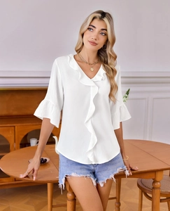 Detail of white V-neck blouse with ruffled trim and flared sleeves in crinkle fabric
