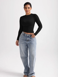 Vue détaillée du haut court noir à manches longues pour femmes avec un jean bleu clair