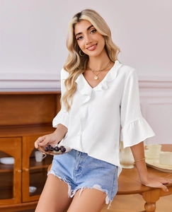 Detail of V-neck ruffle trim and tiered bell sleeves on a white textured chiffon blouse