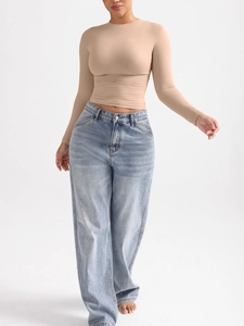 Détail d'un haut moulant à manches longues nude avec un jean bleu clair à taille haute