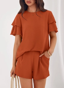 Detail of rust orange two-piece set featuring ruffled sleeves and textured crinkle fabric