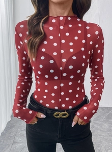 Dettaglio del top rosso trasparente a maniche lunghe in mesh con pois e lupetto
