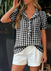 Detailed view of ruffle V-neck and button closure on black white gingham shirt