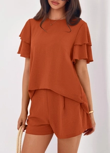 Detail of rust red two-piece set featuring ruffle short sleeves and textured crepe fabric