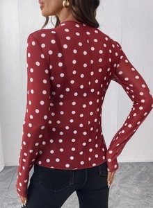 Dettaglio della maglia a rete rossa a pois con maniche lunghe e tessuto semitrasparente