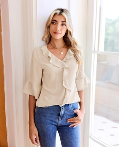Detail of elegant beige chiffon blouse with ruffled V-neckline and lantern sleeve cuffs