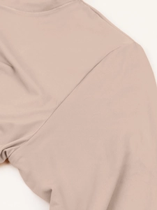 Détail de la couture plate sur l'épaule d'un haut de compression beige à manches longues