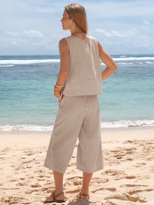 Detail view of khaki striped cotton sleeveless top and wide-leg pants on a sunny beach