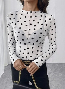 Dettaglio della maglia in rete bianca a pois neri con elegante collo a lupetto arricciato