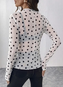 Dettaglio di un top in rete bianca trasparente a pois neri con collo alto sul retro