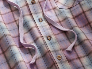 Detail of plaid hooded shirt with brown buttons and light purple drawstrings