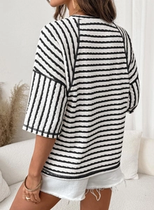 Close-up of black and white striped knit T-shirt fabric with detailed shoulder stitching