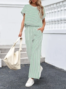 Scatto all'aperto di una donna in completo a due pezzi a righe verdi con pantaloni larghi