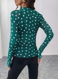 Vista posteriore di un top in rete trasparente verde a pois con maniche lunghe
