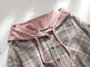 Close-up of a plaid shirt jacket with a pink drawstring hood and brown buttons