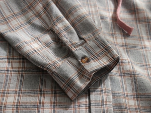 Close-up of orange plaid fabric texture with cuff button and pink hood drawstring
