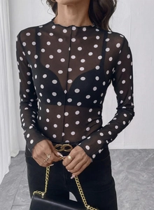 Dettaglio del top in mesh a collo alto con pois bianchi e maniche lunghe eleganti