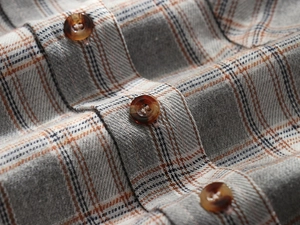 Macro shot of plaid flannel fabric with classic tartan pattern and tortoiseshell buttons