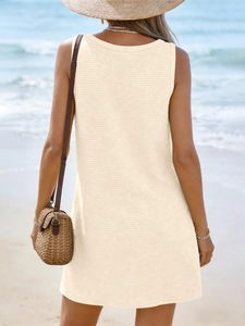 Detail of waffle knit fabric on a beige V-neck sleeveless beach dress in summer setting