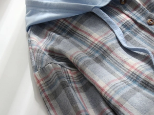 Detail of blue plaid hooded jacket with brown textured buttons and soft fabric texture