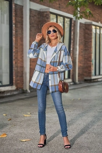 Outdoor street view of a blue and brown plaid flannel hooded shacket with pockets