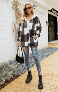 Outdoor shot of a women's hooded plaid coat with pockets and button-down front