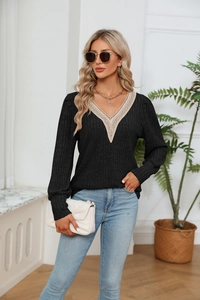 Détail d'un haut noir en tricot avec col en V et bordure en dentelle au crochet beige