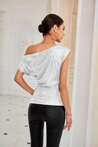 Detail of silver sequined one-shoulder top with metallic shine and draped fabric