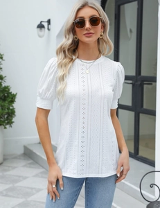Detail of white short sleeve top featuring intricate floral eyelet embroidery and puffed sleeves