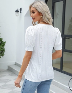 Detail of white short sleeve top featuring intricate hollow embroidery and bubble sleeves