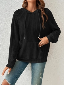 Detail of black ribbed knit hoodie featuring adjustable drawstrings and front kangaroo pocket