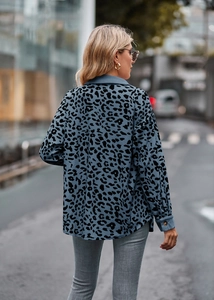 Detailopname van blauwe corduroy stof met luipaardprint en manchetten met knopen