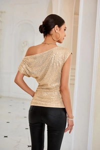 Close-up of golden sequins texture and one-shoulder draping detail on the slim-fit top