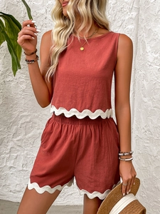 Detail of scalloped white lace trim on terracotta summer linen tank top and shorts set