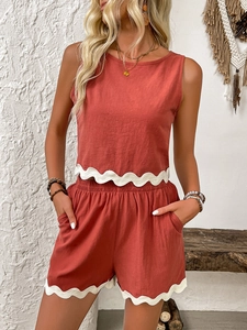 Detail of rust-colored linen two-piece set with white scalloped lace trim on hem and shorts