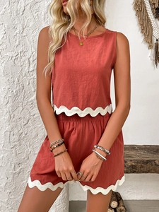 Detail of scalloped white trim on brick red linen tank top and high waist shorts