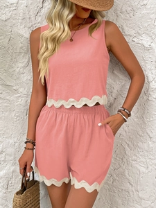 Detail of scalloped white lace trim on the hem of a pink linen two-piece summer set
