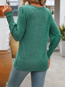 Detail of dark green knit top with puff sleeves and decorative wooden buttons on cuffs
